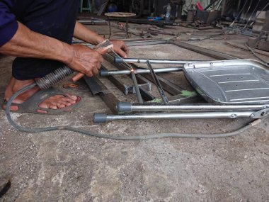 close up, man welding broken chair at his workshop
