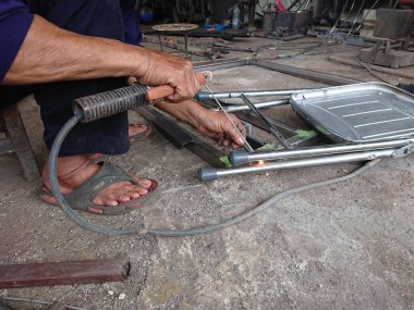 close up, man welding broken chair at his workshop