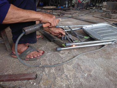 close up, man welding broken chair at his workshop