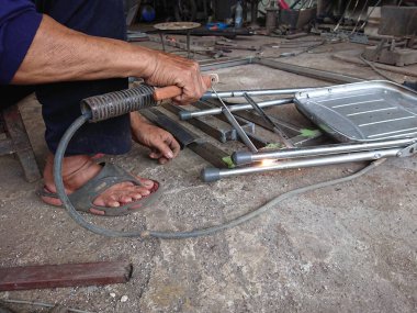 close up, man welding broken chair at his workshop