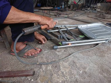 close up, man welding broken chair at his workshop