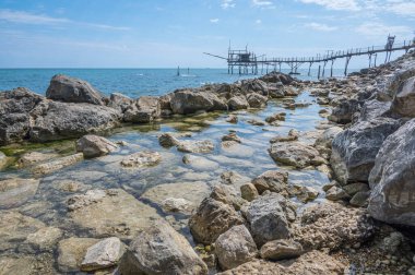 San Vito Chietino - 07-08-2022: Kristal berrak ve mavi denizi ve arka planda trabocco ile Calata Turchina 'nın güzel plajı