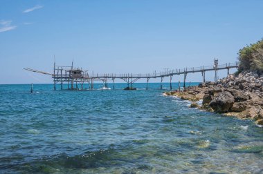 San Vito Chietino - 07-08-2022: Kristal berrak ve mavi denizi ve arka planda trabocco ile Calata Turchina 'nın güzel plajı