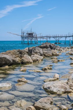 San Vito Chietino - 07-08-2022: Kristal berrak ve mavi denizi ve arka planda trabocco ile Calata Turchina 'nın güzel plajı