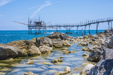 San Vito Chietino - 07-08-2022: Kristal berrak ve mavi denizi ve arka planda trabocco ile Calata Turchina 'nın güzel plajı