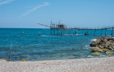 San Vito Chietino - 07-08-2022: Kristal berrak ve mavi denizi ve arka planda trabocco ile Calata Turchina 'nın güzel plajı