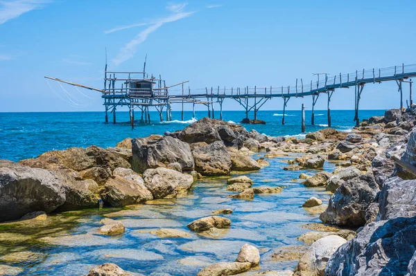 San Vito Chietino - 07-08-2022: Kristal berrak ve mavi denizi ve arka planda trabocco ile Calata Turchina 'nın güzel plajı