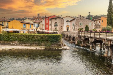 Valeggio, İtalya - 03-02-2022: Borghetto Konsolosu Mincio 'nun güzel renkli evleri gün batımında suyu yansıtıyor