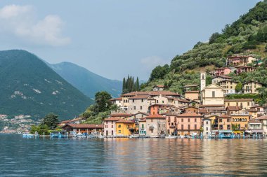 Monte Isola, İtalya - 05-06-2022: Peshiera Maraglio gölünün manzarası Monte Isola 'da suda yansıyan güzel renkli evlerle