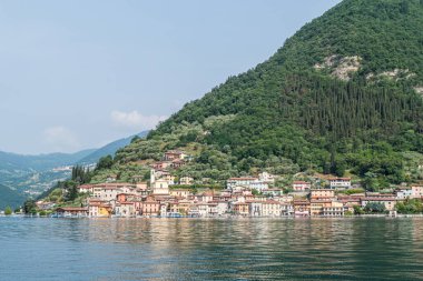 Monte Isola, İtalya - 05-06-2022: Peshiera Maraglio gölünün manzarası Monte Isola 'da suda yansıyan güzel renkli evlerle