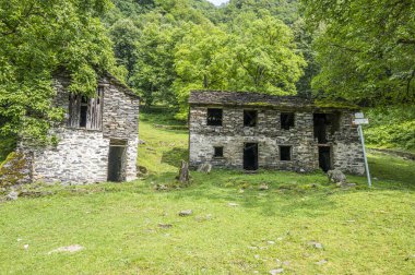 Alplerdeki terk edilmiş bir dağ köyünde harabe taş evler ve değirmenler.