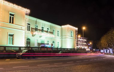 Portovaltravaglia, İtalya - 12-21-2021: Renkli Noel ışıkları ve Portovaltravaglia 'dan geçen arabaların yol ışıklarıyla aydınlatılmış belediye binası