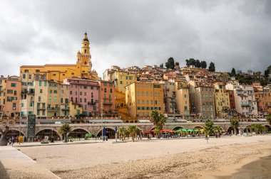 Menton 'un turkuaz suyu ve arka planda güzel renkli evleri olan güzel plajı.