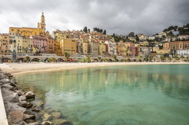 Menton 'un turkuaz suyu ve arka planda güzel renkli evleri olan güzel plajı.