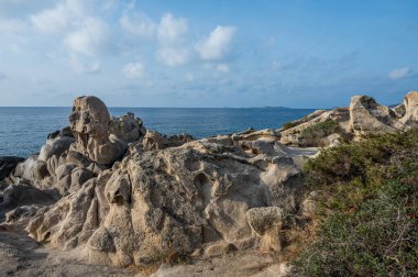 Güneşle aydınlanan rüzgar aşındırmış kayalar Villasimius 'taki güzel Punta Molentis plajında