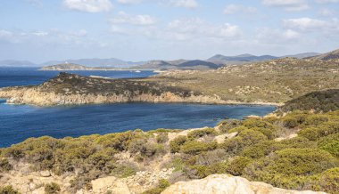 Sardunya 'nın güneybatı kıyılarında kayalıkları, mavi denizi, fiyortları ve beyaz bulutları olan bir manzara.