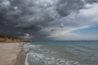 Sardunya 'daki güzel Pinus plajı. Ufukta kum, mavi ve turkuaz su ve fırtına bulutları var.