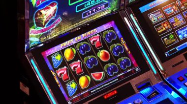 Lima, Peru, 29 Nisan 2023: Canlı bir kumarhanede Ateşli Meyve başlıklı renkli bir kumar makinesi sergileniyor, makaralarında portakal ve limon gibi parlak meyve sembolleri sergileniyor.