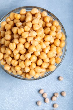 Gri arka planda cam bir kasede kaynamış nohut..