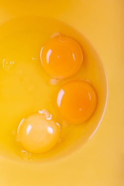 Üst manzara, üç yumurta sarısının sarı bir kasede yakın plan görüntüsü..