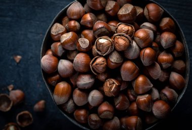 Fındıklı ahşap bir kasenin üstünde. Arka planda bir kasede fındık. Yakın plan. Üst görünüm.