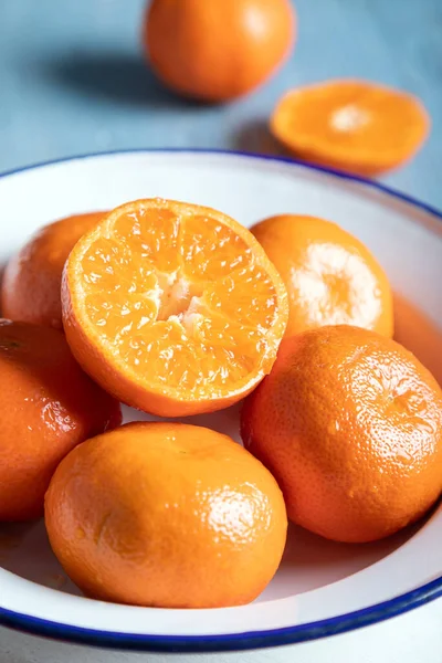 Halved and whole mandarins (tangerines). Fresh ripe whole and sliced mandarin, tangerine or clementine. Whole and halved clementines in a bowl.