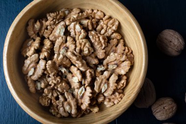 Walnut kernel halves, in a wooden bowl. Close-up, from above, macro food photo.