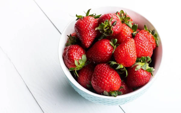 Stock image Bowl of fresh strawberries on a white wooden table. Fresh ripe delicious strawberries in a white bowl on a wooden background. 