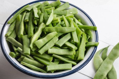 Beyaz ahşap bir masada kasede taze yeşil fasulye. Ahşap arka planda bir kase yeşil fasulye.. 