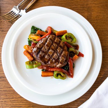 Beyaz bir tabakta ızgara biftek ve sebze. Soslu ızgara biftek.. 