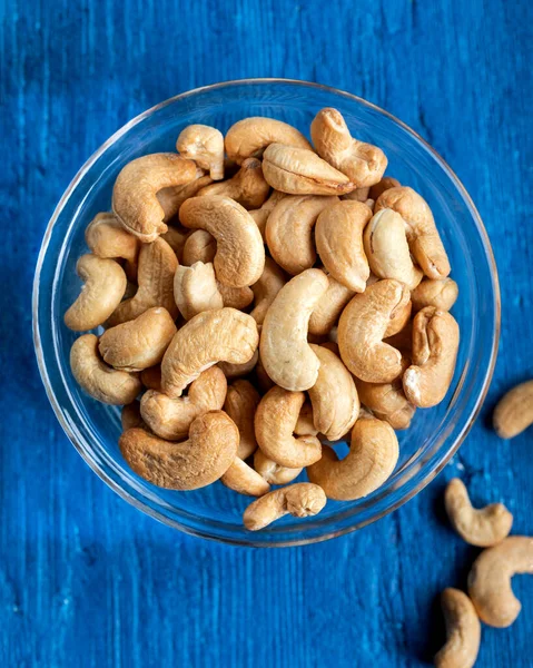 stock image Tasty cashew nuts in a bowl on a wooden table, top view.Bowl with cashew nuts on a wooden table, flat lay. 