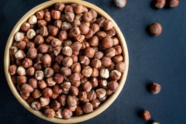 Siyah arka planda çiğ fındık. Arka planda bir kase fındık..