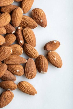 Beyaz arka planda izole edilmiş bir yığın badem. Badem yığını mermer zemin üzerinde izole edilmiş. Üst görünüm.