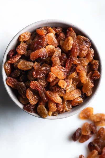 stock image Raisins in ceramic bowl on marble background. Dried grapes on white background. Top view.