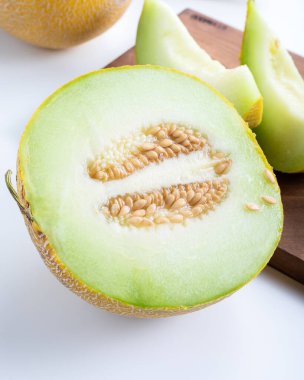 Beyaz arka planda yarım kavun ve dilimlenmiş kavun parçaları..