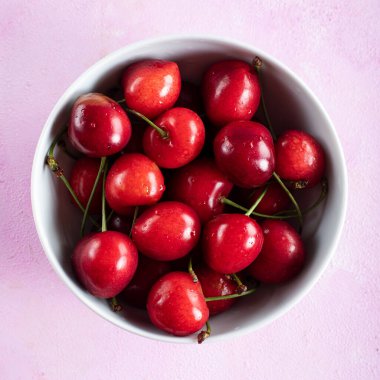 Beyaz kasede taze kiraz meyvesi, pembe arka planda..