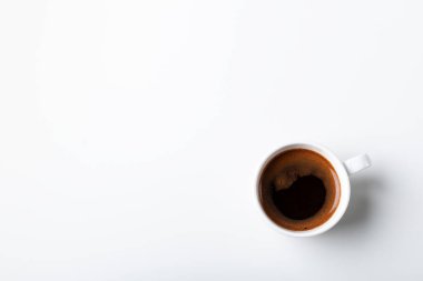 Beyaz arka planda bir fincan sade kahve. Beyaz masadaki beyaz seramik fincanda siyah espresso kahvesi, üst manzara, boşluğu kopyala. 