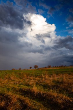Sonbahar manzarası. Koyu bulutlar ve mavi gökyüzü kırsalda..
