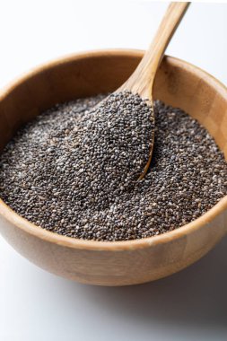 Beyaz arka planda tahta kasede Chia tohumları. Seçici odak.