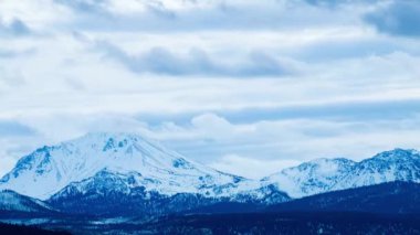 Lassen Dağı ve Kaos Kayalıkları 'nın üzerinde hareket eden karamsar bulutlarda kısa bir zaman atlaması. Kaliforniya, Lassen County 'deki Hat Creek Rim' de gün batımında kaybolan akşam ışığında yakalandı..