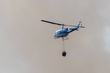 REDDDDING CALIFORNIA 10 AĞUSTOS 2024 Bir Çan UH1 helikopteri Mary Gölü 'nden suyla dolu olarak Lower Springs / Keswick yakınlarında alçak ateşin dumanına doğru uçuyor.