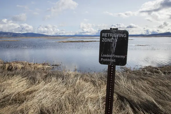 Siskiyou İlçesi 'ndeki Aşağı Klamath Vahşi Yaşam Sığınağı' ndaki bir tabela avcılara bir alanın sadece ele geçirme için açık olduğunu ve içeri girmek için silahlarını boşaltmaları gerektiğini tavsiye ediyor.