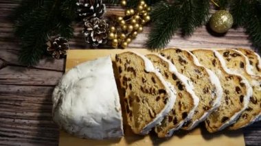 Dilimlenmiş Noel pastası masanın üzerinde duruyor. Panorama. Arka planda Noel süsleri ve Noel oyuncakları var. Noel ve yeni yıl için tatlı ikram