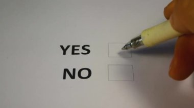 Kalem tutan el, seçim için kağıt oy pusulasına EVET kutusunu seçer ve işaretler. Kasım ayında bir oy pusulası ve oy kullanma merkezinde mavi bir kalem. ABD Kongresi 'ne ara seçimler