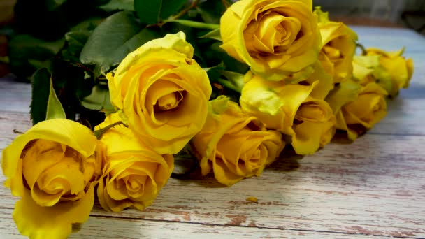 一束花盛开的黄色大玫瑰花躺在木制的表面上 节日贺词的概念 — 图库视频影像