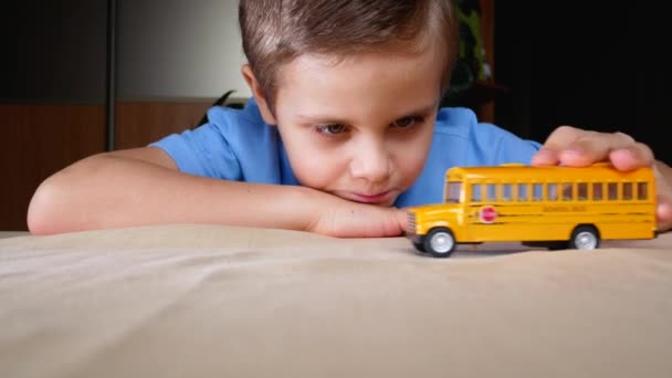 7歳の可愛い男の子がテーブルの上でスクールバスを転がし レッスンのために学校に行くことを夢見ています Covid 19パンデミック隔離時のロックダウン 自己分離 — ストック動画