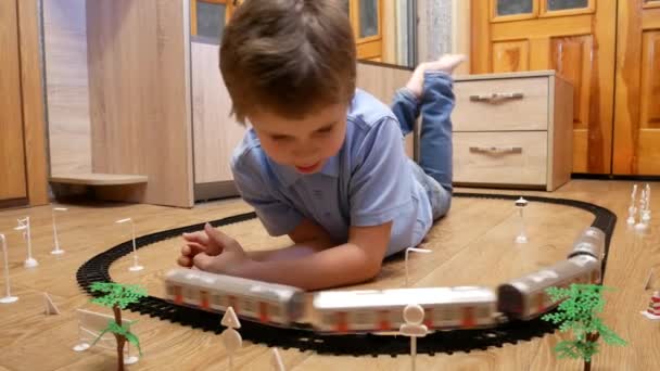 Милий Хлопчик Років Грає Дитячою Залізницею Лежить Підлозі Дивиться Мандрівні — стокове відео