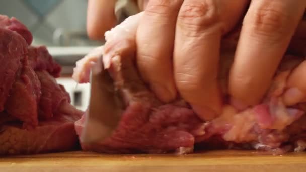 女性の手はキッチンの板にナイフでジューシーな赤豚の肉の作品をカットします 肉料理の準備 豚肉料理 — ストック動画