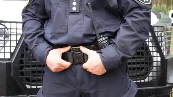 Polis Står Bakgrunden Polisbil Och Håller Fast Vid Ett Hölster — Stockvideo