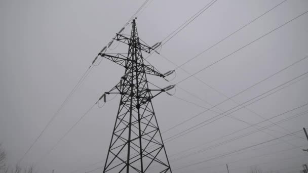 曇り空に対する大きな金属製の高電圧タワー 消費者への電気の生産と輸送 エネルギーシステムに打撃を与える 停電だ 家の中の電気と光 — ストック動画